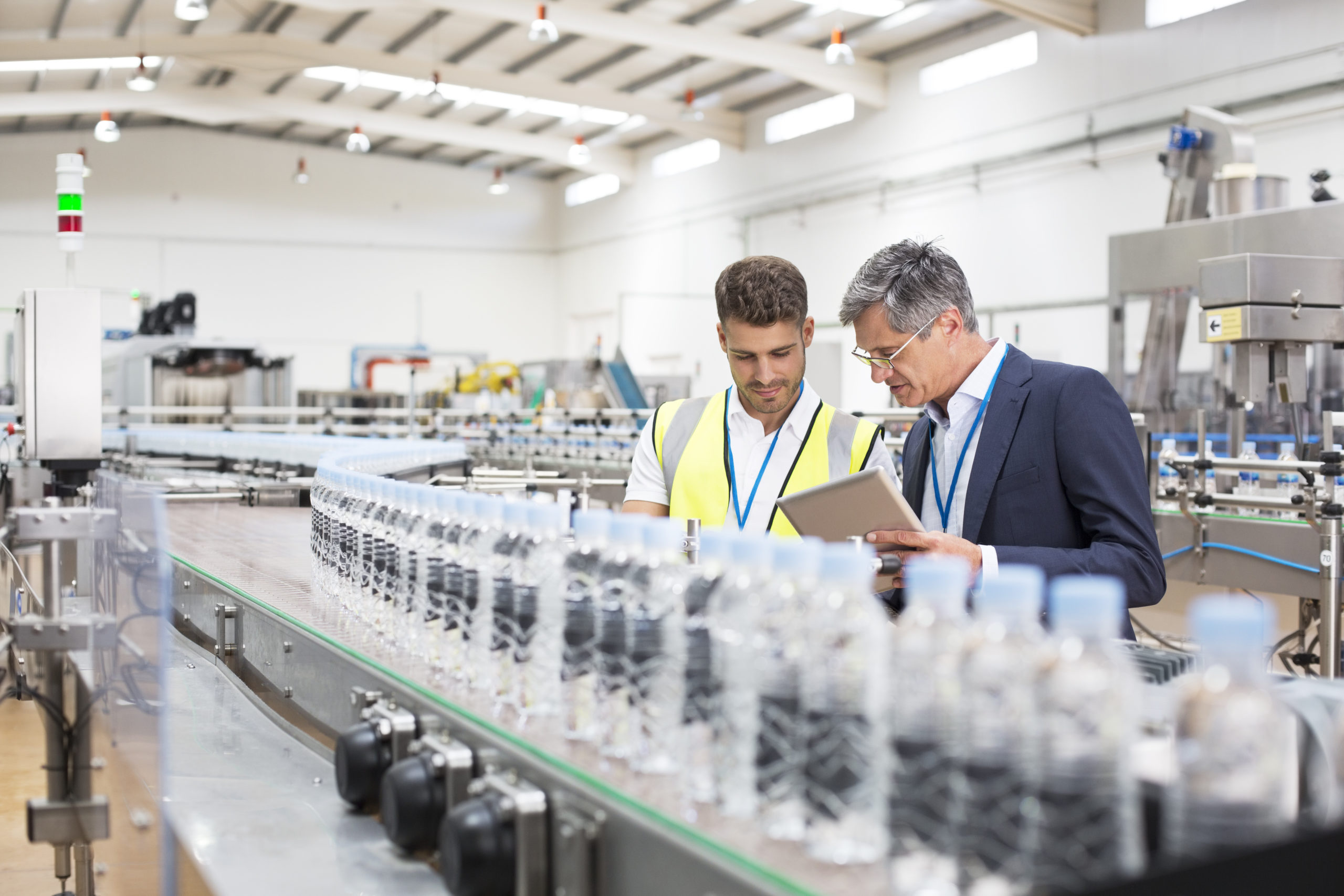 Supervisor and manager watching plastic bottles on conveyor belt Supervisor and manager watching plastic bottles on conveyor belt
